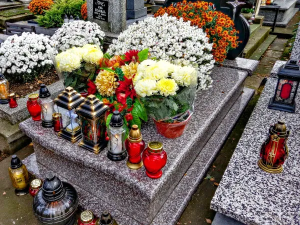 Kwiaty i zapalone świece na cmentarzu w Dzień Wszystkich Świętych